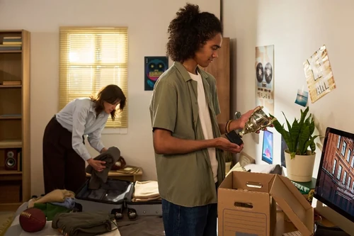 A mother helping her son unpack in his dorm room.